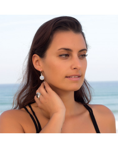 Boucles d'oreille en pierre de lune de forme ronde serties d'argent massif portée par femme